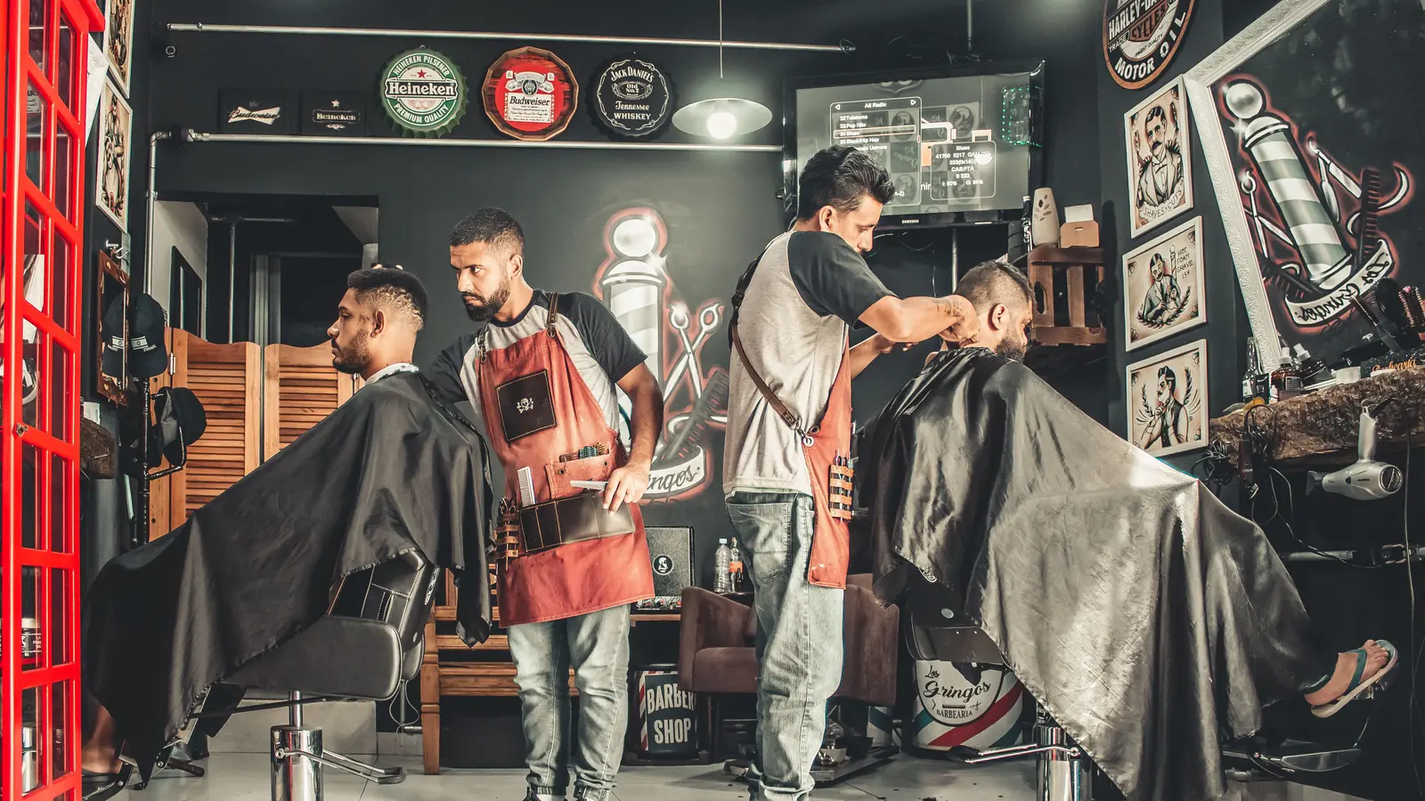Barbers cutting two customers' hair in a busy barbershop