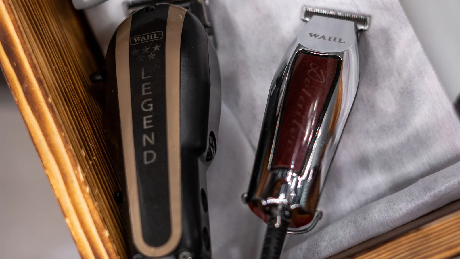 A Wahl clipper and a Wahl trimmer lying in a barber's wooden drawer
