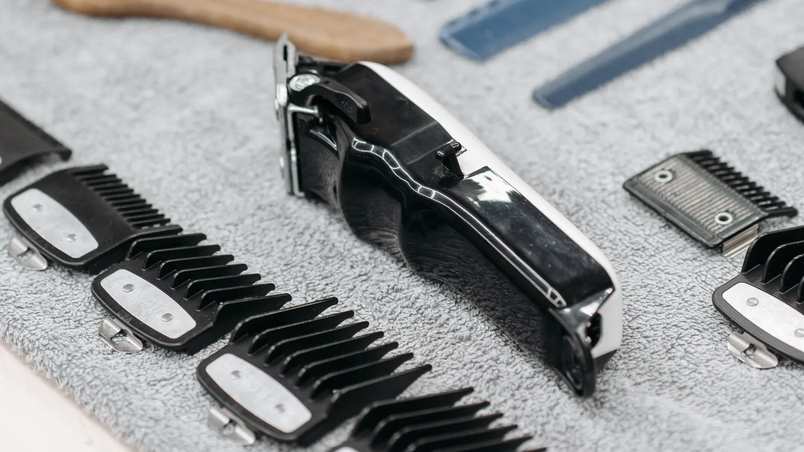 Hair clipper with a row of plastic clipper guards laid out on a grey towel