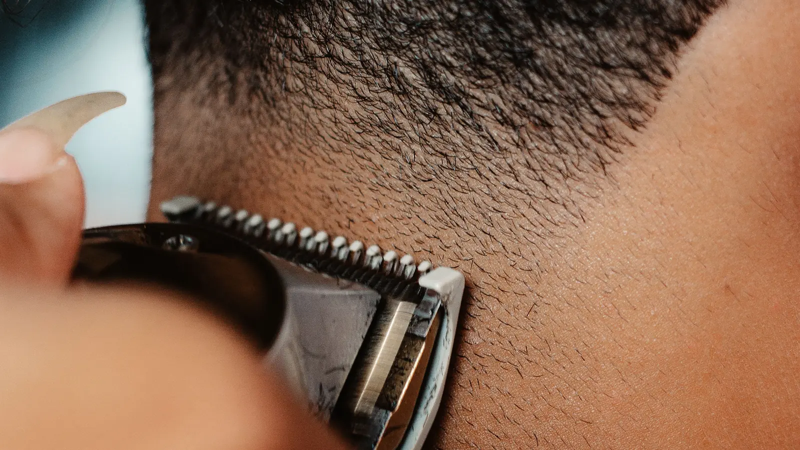 Close-up of a clipper fading the hair at the back of a man's neck