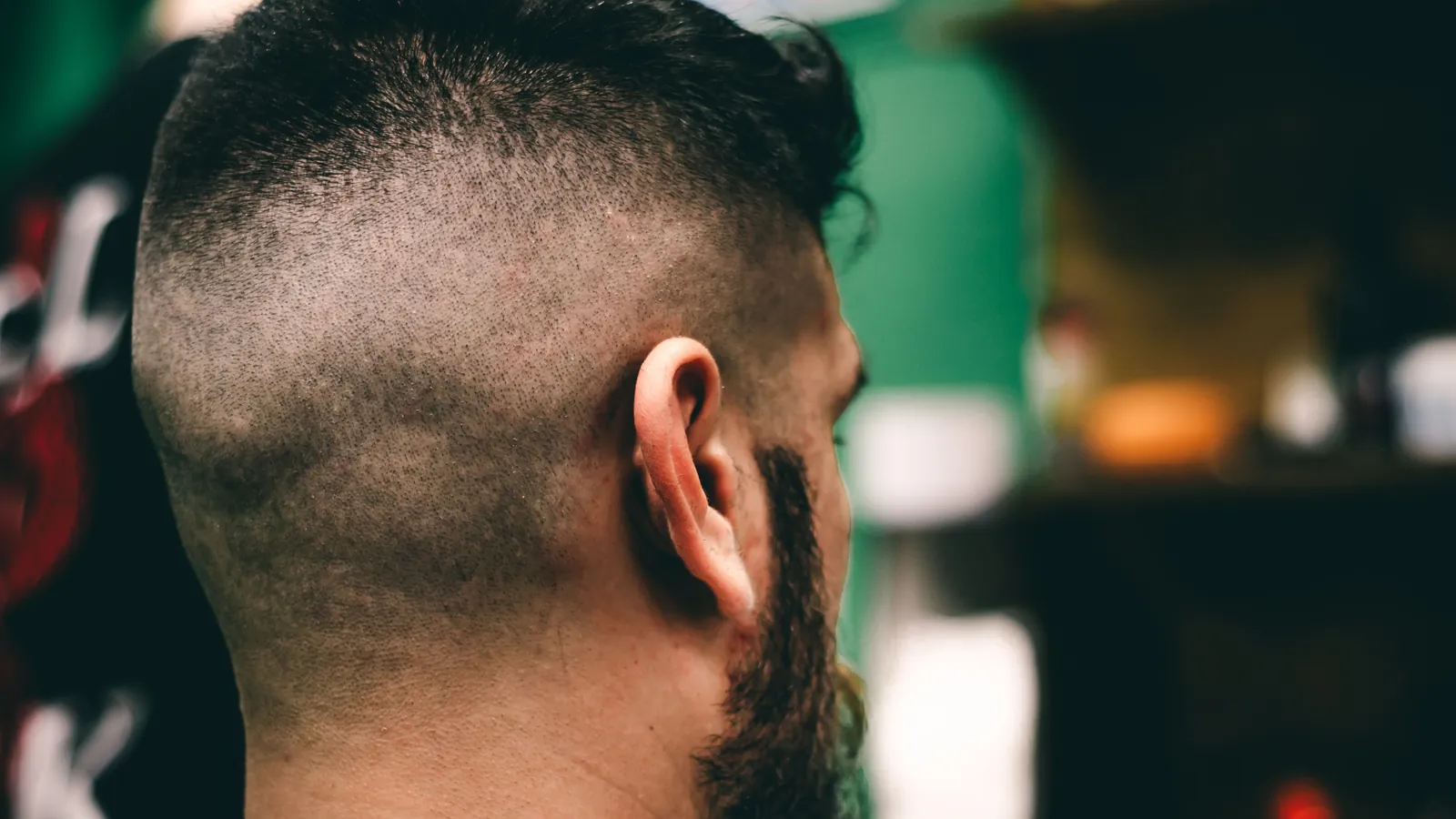 Back of a man's head showing a fresh high fade with longer hair on top, in a barbershop